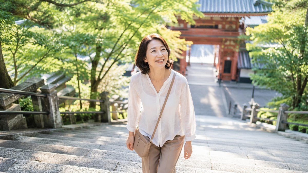 旅行先で軽やかに石段を上る50代女性のイメージ