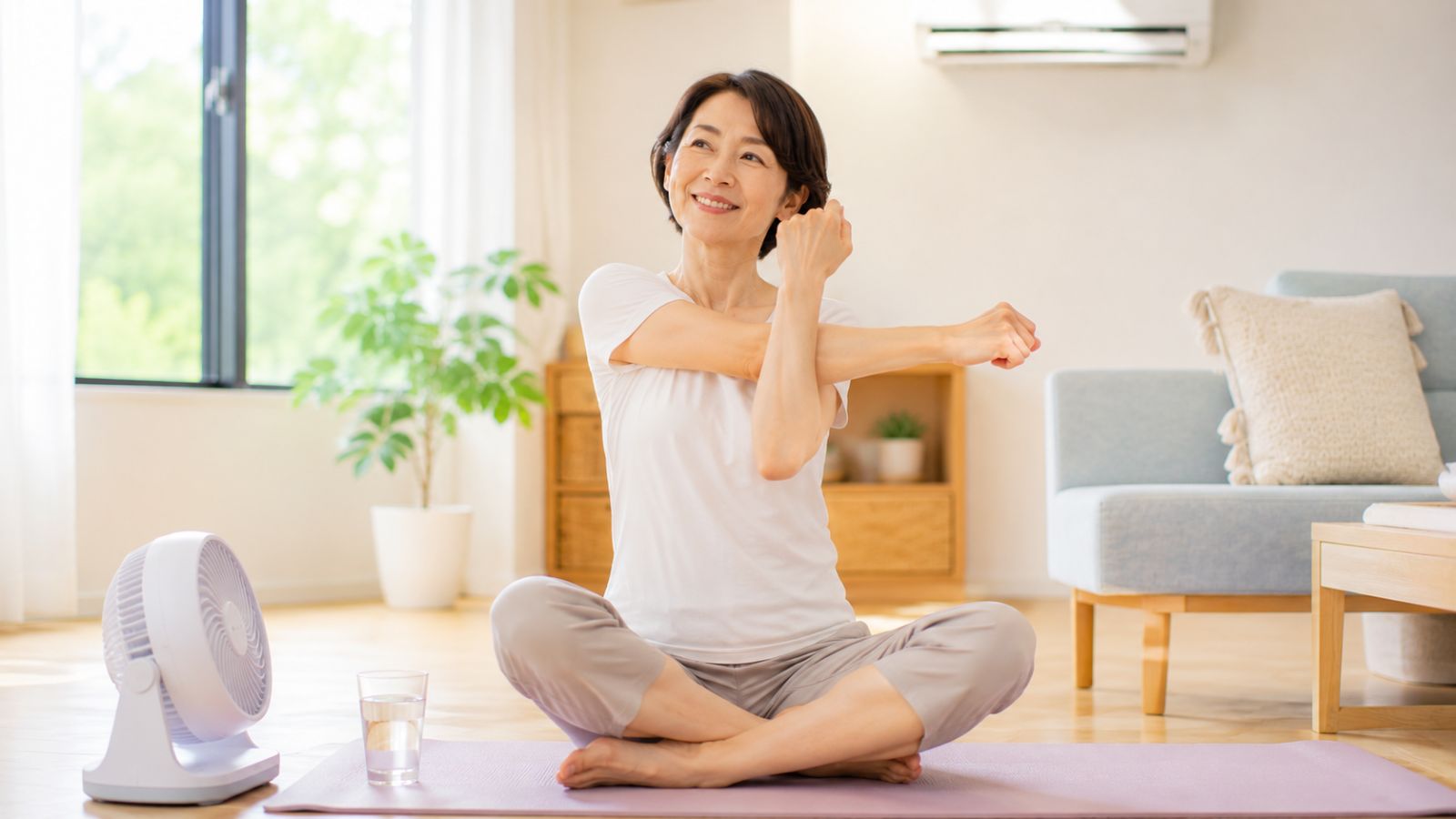 暑い夏でも笑顔で軽いストレッチをする40代女性のイメージ